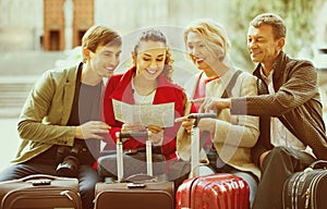 Family of four with luggage checking direction in map