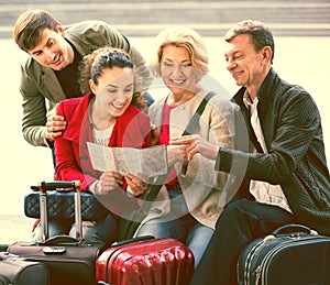 Family of four with luggage checking direction in map