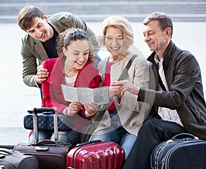 Family of four with luggage checking direction in map