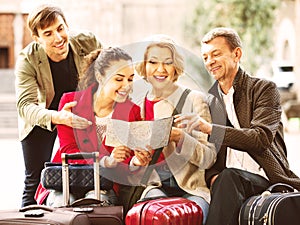 Family of four with luggage checking direction in map