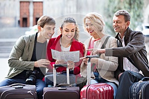 Family of four with luggage checking direction in map