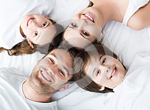 Family of four lying on bed