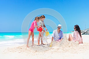 Family of four making sand castle on their beach vacation