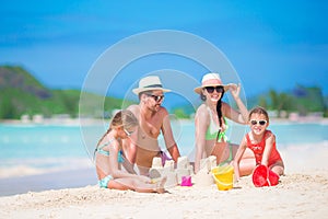 Family of four making sand castle at tropical white beach