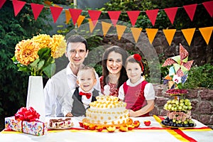 Family of four people father mom son and daughter celebrates daughter`s birthday three years sitting at a festive decorated table