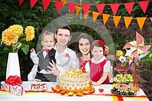 Family of four people father mom son and daughter celebrates daughter`s birthday three years sitting at a festive decorated table