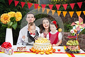 Family of four people father mom son and daughter celebrates daughter`s birthday three years sitting at a festive decorated table