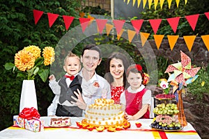 Family of four people father mom son and daughter celebrates daughter`s birthday three years sitting at a festive decorated table