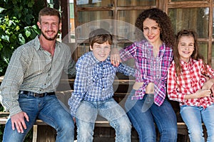 family of four sitting on a bench on background of