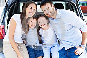 Family of four sitting in car trunk