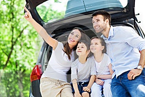 Family of four sitting in car trunk