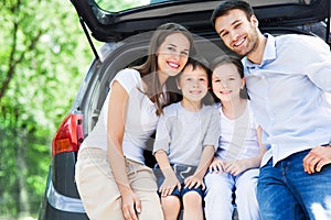 Family of four sitting in car trunk