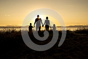 Family of four at sunset shadow black backlit