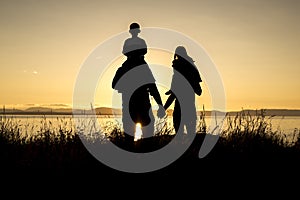 Family of four at sunset shadow black backlit