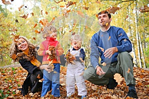 Family of four throw autumnal leaves