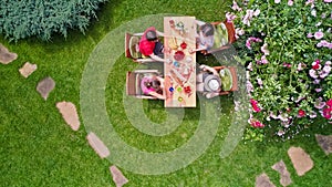 Family and friends eating together outdoors on summer garden party. Aerial view of table with food and drinks from above