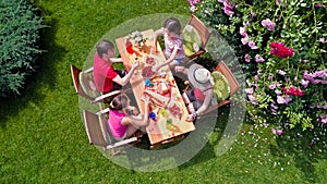 Family and friends eating together outdoors on summer garden party. Aerial view of table with food and drinks from above