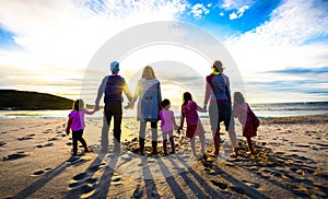 Family and friends group standing on the beach holding hands