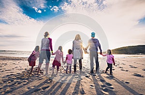 Family and friends group standing on the beach holding hands