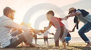 Family friends having fun on the beach at sunset - Fathers, mothers, children and uncles playing together - Focus on bodies - Love photo