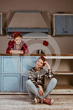 Family, friendship and people concept - happy mother with little daughter. With red lips in a bandana have fun in the home kitchen