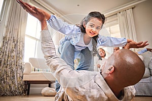 Family, fun and a daughter flying with dad on the floor of a living room in their home together for bonding. Smile