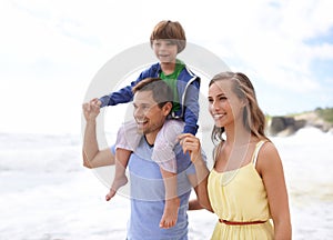 Family, fun and happy while walking at beach for travel, fun or holiday in summer with a smile. Man, woman and child or