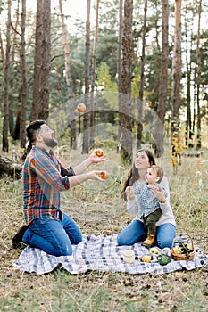 Family, fun and leisure concept. Portrait of happy family sitting on checkered plaid in autumn forest. Pretty mom and