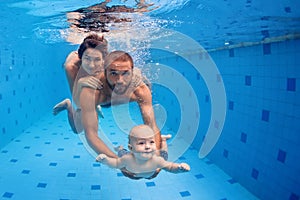 Family fun in swimming pool - mother, father, baby dive underwater