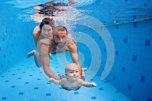 Family fun in swimming pool - mother, father, baby dive underwater photo