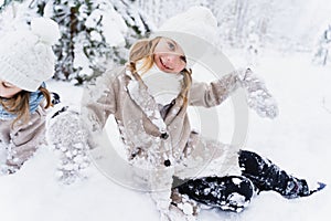 Family fun,winter kids activity in snowy mittens. Stylish smiling girl in white hat, coat, scarf, snood.Happy fashionable children