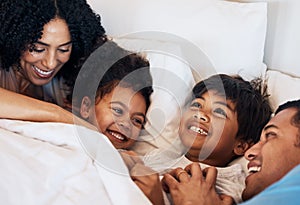 Family, funny and children laughing in bed at home in the morning together with their happy parents. Relax, love or