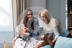 Family gathering. Father, Mother and daughter in the family home, reminisce about the past by looking at old photos from their photo