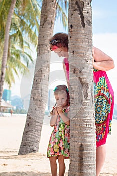 Family, generation - happy smiling grandmother and little granddaughter stand near the palm on the beach