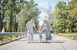 Family, generation and people concept - happy smiling grandmother, grandfather and little granddaughter walking at park