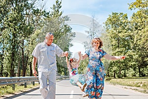 Family, generation and people concept - happy smiling grandmother, grandfather and little granddaughter walking at park