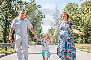 Family, generation and people concept - happy smiling grandmother, grandfather and little granddaughter walking at park