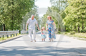 Family, generation and people concept - happy smiling grandmother, grandfather and little granddaughter walking at park