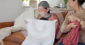 Family, girl and mother on a sofa with laundry, clothes and fold in a living room, happy and bonding. Happy family