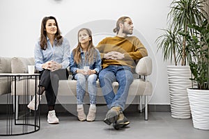 Family with a girl sitting on a couch at the waiting room of the clinic