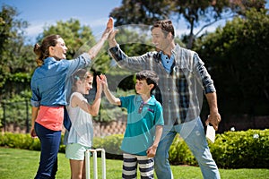 Family giving high five to each other while playing cricket