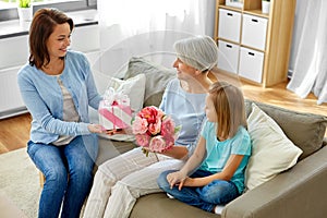 Family giving present and flowers to grandmother