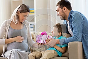 Family giving present to pregnant mother at home