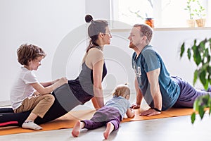 Family goes sports at home together. Mom dad baby doing yoga exercises