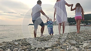 Family going to the beach in slow motion. Baby`s first steps on the sea shore.