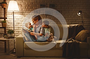 Family before going to bed mother reads children book about lamp