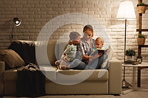 Family before going to bed mother reads children book about lamp