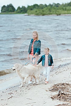 family with golden retriever dog on walk near the sea