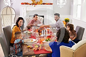 Family With Grandparents Enjoying Thanksgiving Meal At Table