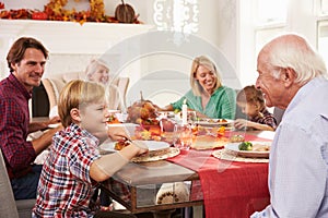 Family With Grandparents Enjoying Thanksgiving Meal At Table photo